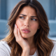 Woman holding her cheek during recovery after a tooth extraction