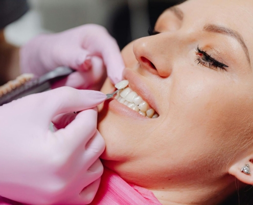 Dentist holding a porcelain veneer beside a patient's natural front tooth