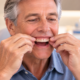 Man adjusting a new upper denture in his mouth