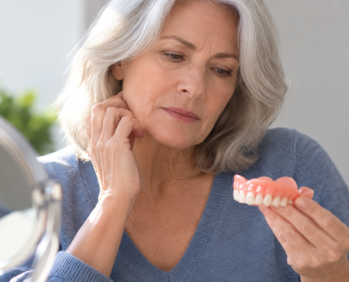 Woman examining a loose denture that no longer fits comfortably